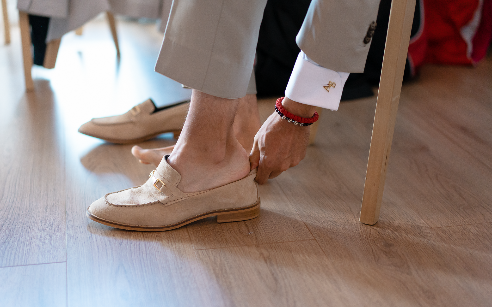 Le futur marié enfile ces chaussure sans chaussette. Son bouton de manchette est bien visible, couleur or et représente ses initiales.